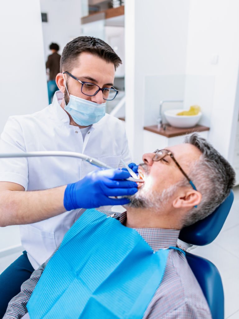 Male dentist examining mature male patient in dental clinic